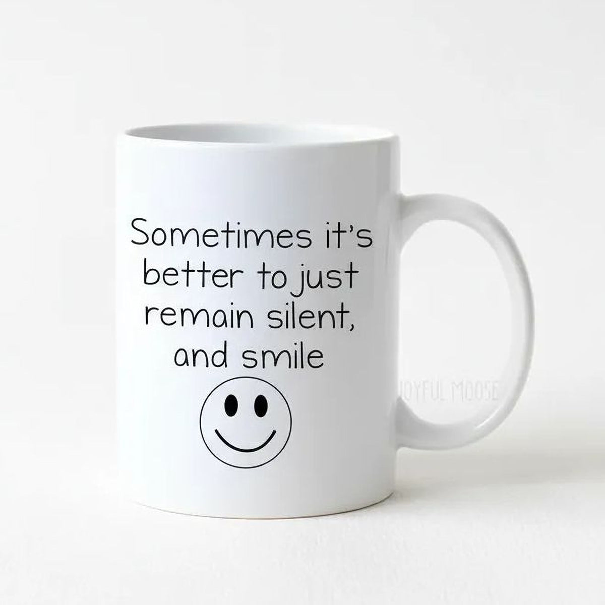 A white ceramic mug with a black smiley face and text printed on it.
