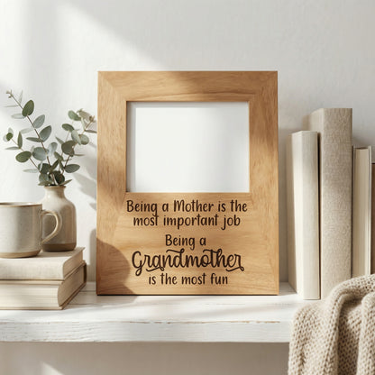 A wooden picture frame with a message about being a mother, placed on a shelf next to a stack of books and a plant.
