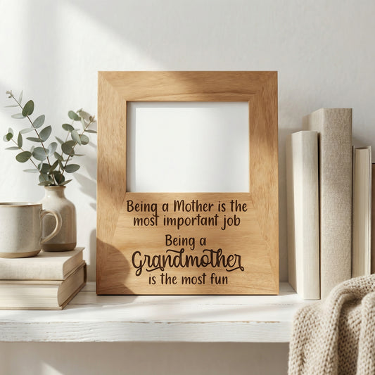 A wooden picture frame with a message about being a mother, placed on a shelf next to a stack of books and a plant.