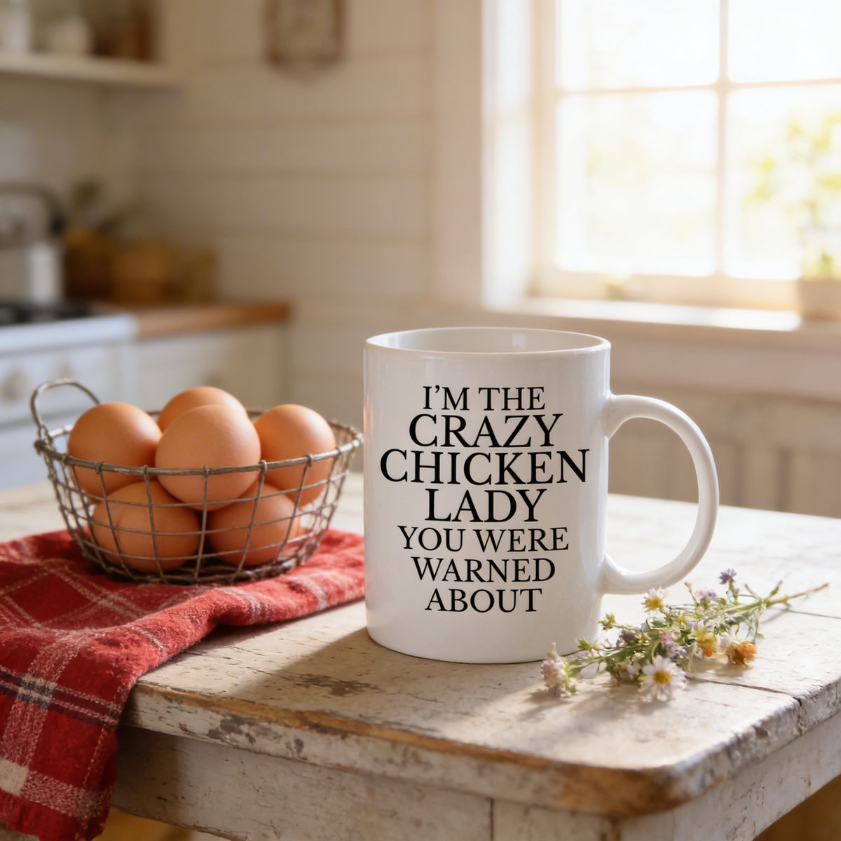 A white mug with the text "I'm the CRAZY CHICKEN LADY YOU WERE WARMED ABOUT" printed on it, placed on a wooden table next to a basket of eggs and a red and white checkered cloth.