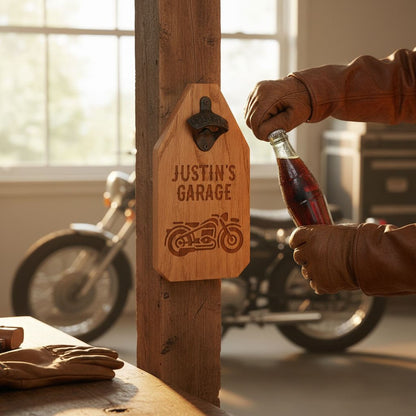 A person is holding a bottle of soda and a wooden beer bottle opener with the inscription "JUSTIN'S GARAGE" on it, standing in front of a motorcycle.