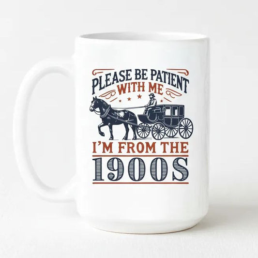 A white ceramic mug with a printed design featuring a horse-drawn carriage and text that reads "PLEASE BE PATIENT WITH ME I'M FROM THE 1900S".