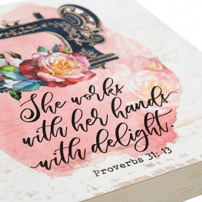 a close-up of a pink and white floral design with a black and gold sewing machine and a quote from Proverbs 31:13.