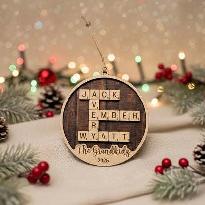 A wooden ornament with letters arranged in a Scrabble-like game style, surrounded by Christmas decorations and pine cones.