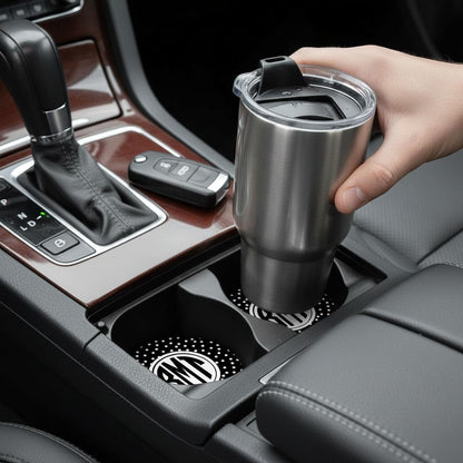 A person's hand is holding a stainless steel thermos in the car's cup holder.