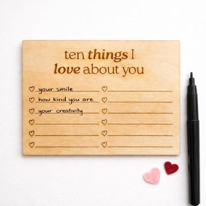 a wooden card with a list of ten things someone might love about them, along with a pen and two small heart-shaped objects.