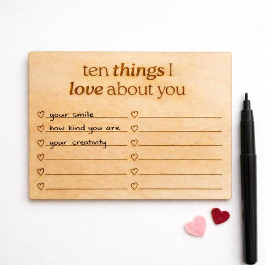 a wooden card with a list of ten things someone might love about them, along with a pen and two small heart-shaped objects.