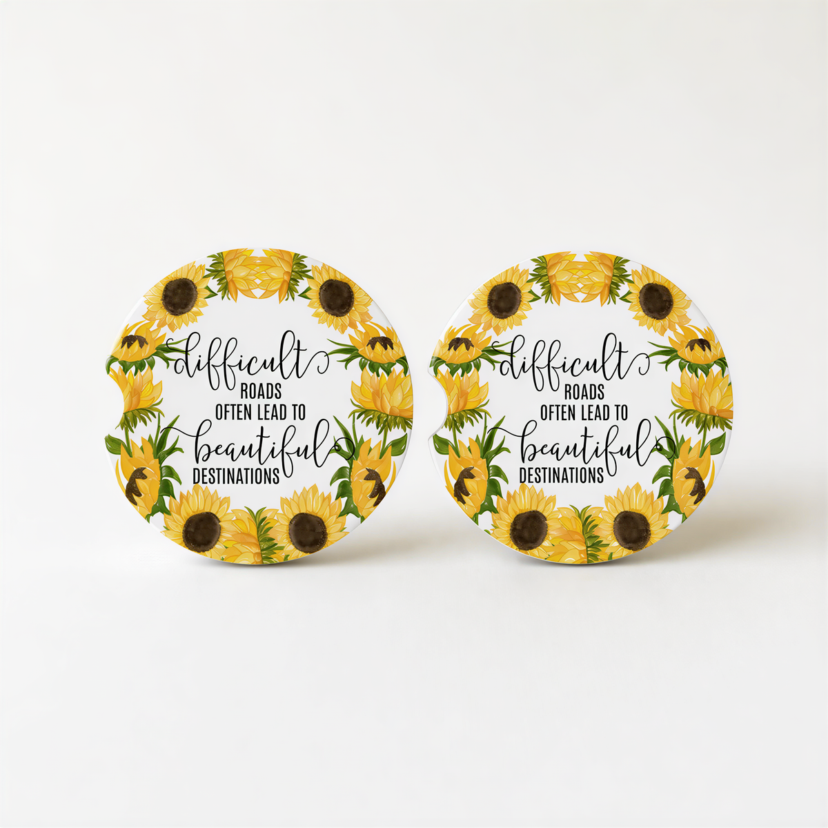 two round coasters with a sunflower design and text on them.