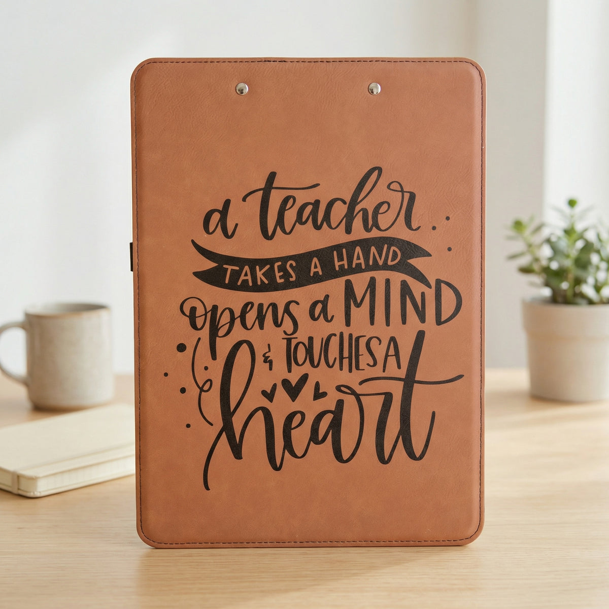 A brown clipboard with a motivational quote about a teacher.