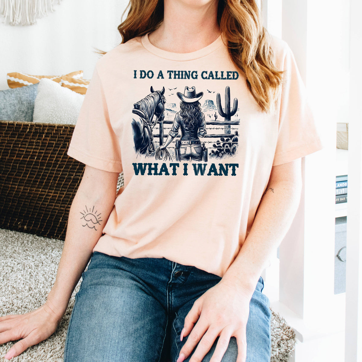 A woman wearing a t-shirt with a graphic design of a woman riding a horse and a cactus, along with the text "I DO A THING CALLED WHAT I WANT".