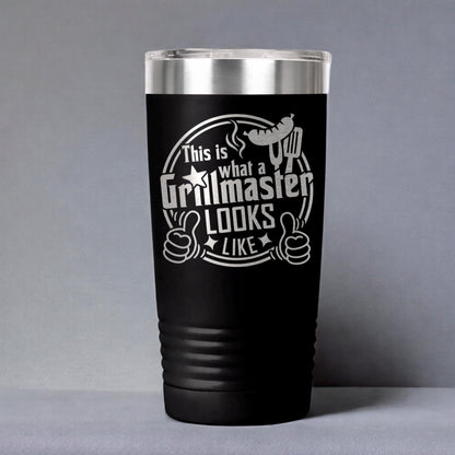 A black tumbler with a silver lid, featuring a humorous text and graphic design that reads "This is what a Grillmaster looks like like".