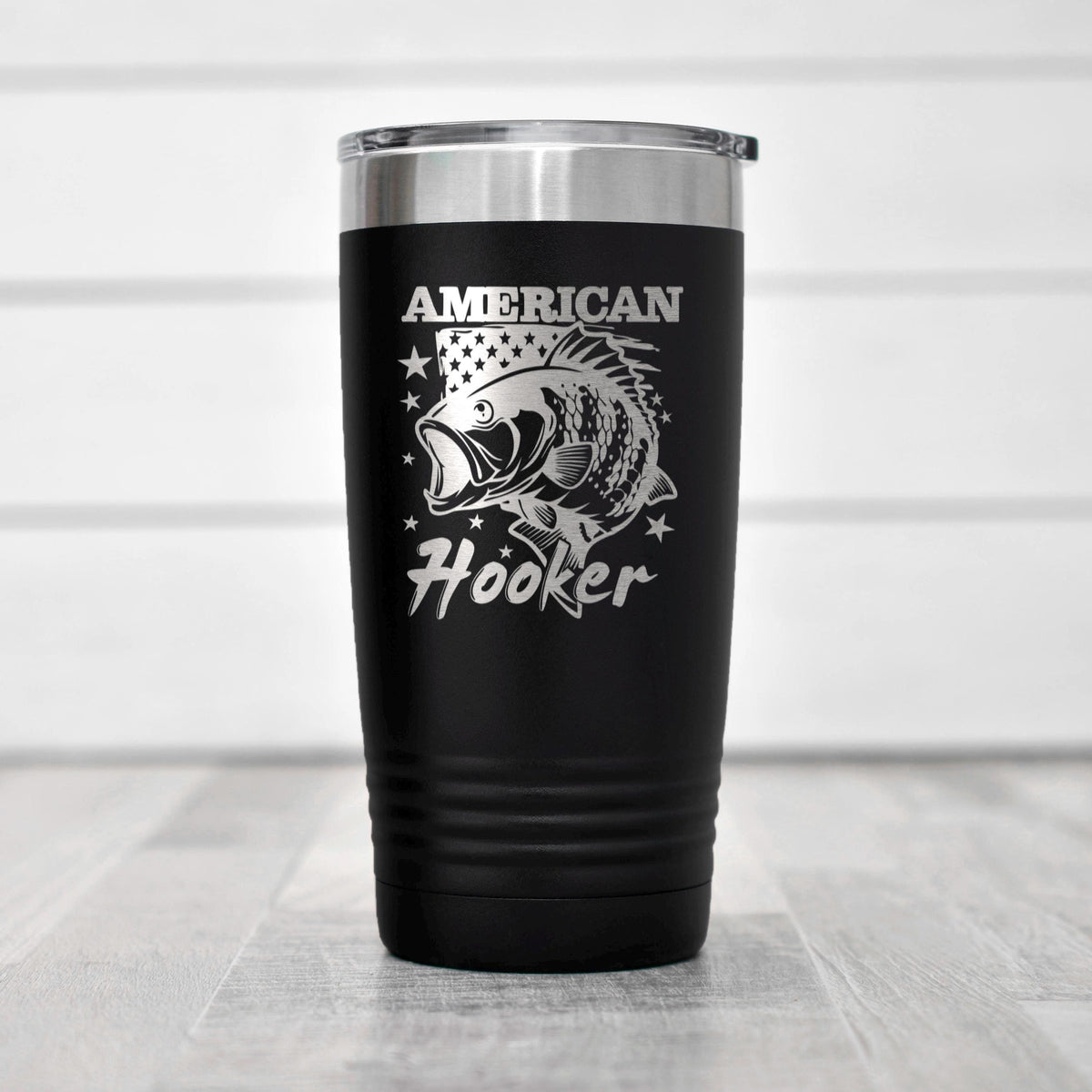 A black insulated tumbler with a silver lid, featuring a silver fish design and the text "AMERICAN Hooker" printed on it.