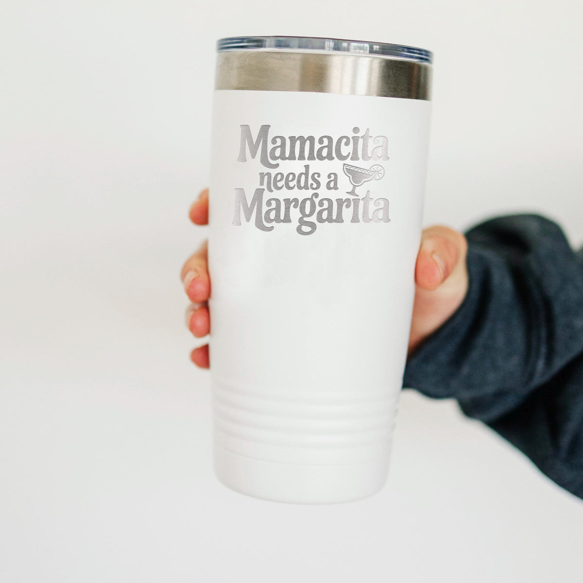 A person's hand holding a white insulated tumbler with the text "Mamacita needs a Margarita" printed on it.