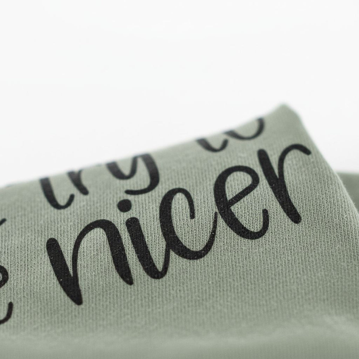 A close-up view of a fabric with the text "TRY TO BE NICE" printed on it.