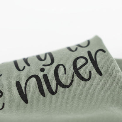 A close-up view of a fabric with the text "TRY TO BE NICE" printed on it.