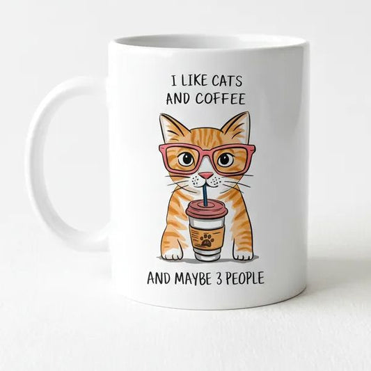 A white ceramic mug with an illustration of a cat wearing glasses and holding a coffee cup, accompanied by the text "I LIKE CATS AND COFFEE AND MAYBE 3 PEOPLE".