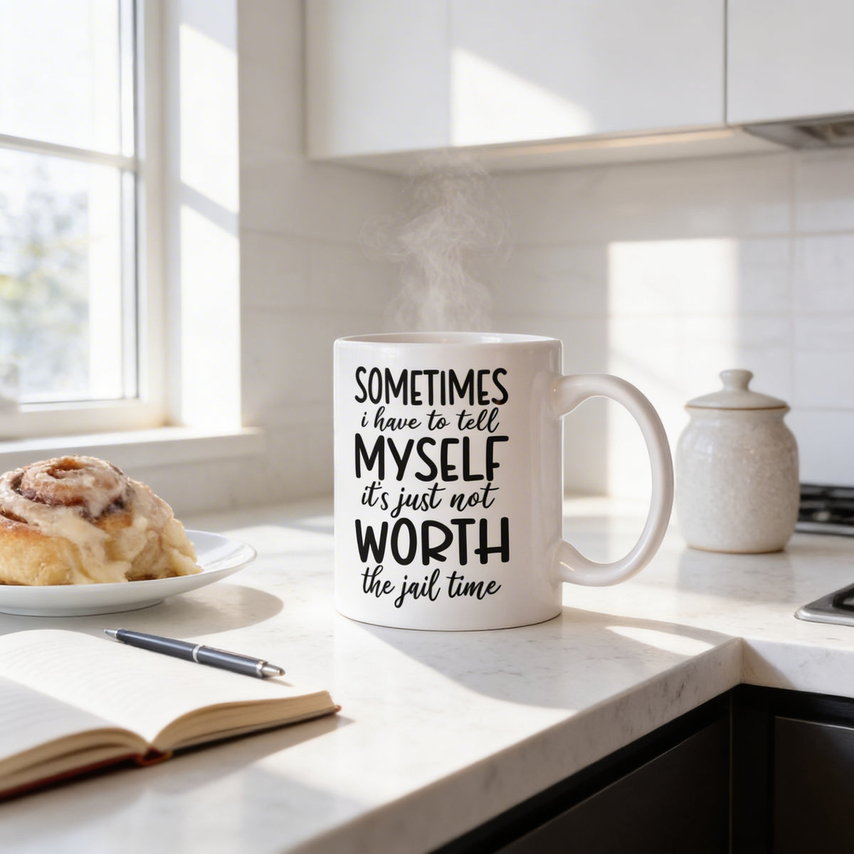 A mug with a humorous text printed on it sits on a kitchen counter, accompanied by a plate of cinnamon rolls and a pen.