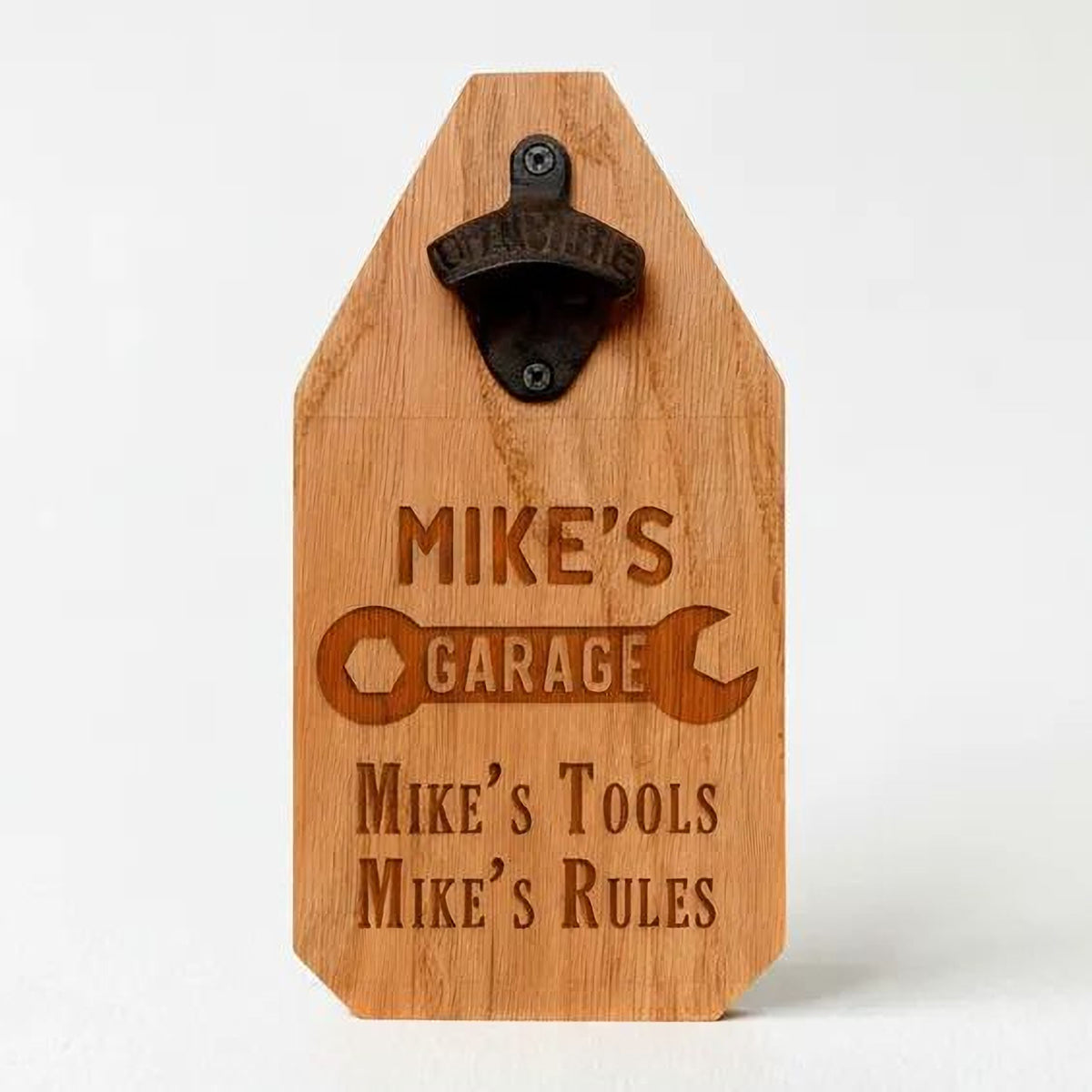 A wooden beer tap holder with a metal bottle opener attached to it. The tap holder has a personalized message engraved on it, which reads "Mike's Garage Mike's Tools Mike's Rules".