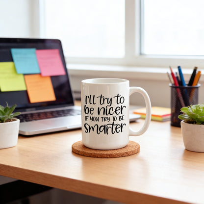 A white mug with a humorous text printed on it, placed on a cork coaster on a wooden desk. In the background, there is a laptop with sticky notes on it, and a small potted plant is visible on the desk.