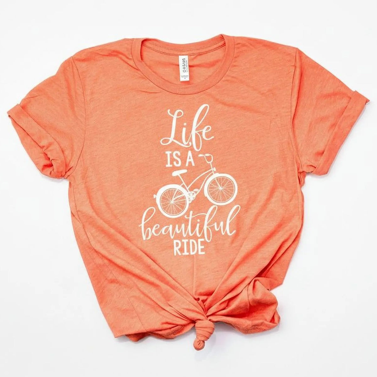 a bright orange t-shirt with a white bicycle graphic and the text "Life is a beautiful ride" printed on it.